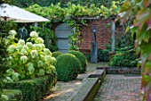 SURREY GARDEN DESIGNED BY ANTHONY PAUL: VIEW TO BRICK TERRACE WITH BEDS OF WHITE HYDRANGEA ANNABELLE AND TABLE AND CHAIRS - PATIO, SUMMER, COUNTRY GARDEN, FORMAL, SEPTEMBER