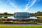 RHS GARDEN, WISLEY: THE GLASS HOUSE AND LAKE WITH BORDERS BY TOM STUART - SMITH - SUMMER, SEPTEMBER, EVENING LIGHT