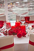 SALTWATER, NORFOLK : DESIGNER KAREN MOORE - CHRISTMAS, DECEMBER, WINTER - THE DINING ROOM IN RED AND WHITE - TABLE, CHAIRS, RIBBONS, DECORATION, LIGHTS, CANDLES, DINNER, WINE GLASS