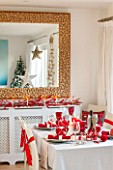 SALTWATER, NORFOLK : DESIGNER KAREN MOORE - CHRISTMAS, DECEMBER, WINTER - THE DINING ROOM IN RED AND WHITE - TABLE, CHAIRS, RIBBON, DECORATION, LIGHTS, CANDLES, DINNER, CORK MIRROR