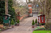CHELSEA PHYSIC GARDEN, LONDON: VIEW ALONG PATH TO THE FRONT GATE OF THE GARDEN WITH BOX TOPIARY TREES IN TERRACOTTA CONTAINERS