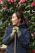 CHISWICK HOUSE CAMELLIA SHOW / COLLECTION, CHISWICK HOUSE AND GARDENS, LONDON: YUKO - A JAPANESE GARDENER / VOLUNTEER  IN THE CAMELLIA HOUSE - CONSERVATORY, LADY, WOMAN