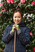 CHISWICK HOUSE CAMELLIA SHOW / COLLECTION, CHISWICK HOUSE AND GARDENS, LONDON: YUKO - A JAPANESE GARDENER / VOLUNTEER  IN THE CAMELLIA HOUSE - CONSERVATORY, LADY, WOMAN