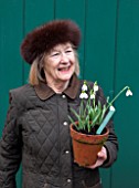 RODE HALL AND GARDENS, CHESHIRE: LADY ANNE BAKER WILBRAHAM HOLDING A TERRACOTTA CONTAINER PLANTED WITH SNOWDROPS - GALANTHUS. WOMAN, LADY