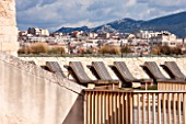 MUCEM, MARSEILLES, FRANCE: THE JARDIN DE MIGRATIONS, FORT SAINT - JEAN. SUN LOUNGERS ON THE ROOF GARDEN WITH VIEW OF MARSEILLES BEHIND. TERRACE, SEATS, SEATING, BENCH, BENCHES