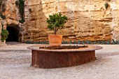 MUCEM, MARSEILLES, FRANCE: THE JARDIN DE MIGRATIONS, FORT SAINT - JEAN. RUSTY METAL POOL / POND WITH ORANGE TREE IN TERRACOTTA CONTAINER