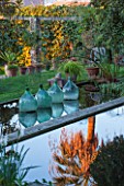 CLOS DU PEYRONNET, MENTON, FRANCE: POOL / POND WITH REFLECTION OF PALM TREE IN WATER. GLASS BOTTLES / JARS IN WATER. ORNAMENT, FEBRUARY, MEDITERRANEAN