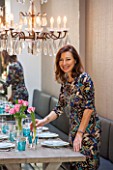 SALLY STOREY HOUSE, LONDON: SALLY STOREY IN DINING AREA - WOODEN TABLE, DINING CHAIRS, CHANDELIER AND BANQUETTE SEATING, MIRROR, TULIPS. ENTERTAINING, SEAT, SEATS, LIGHTING, LIGHTS