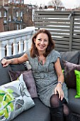 SALLY STOREY HOUSE, LONDON: SALLY STOREY SITTING ON HER ROOF TERRACE SURROUNDED BY LIME GREEN CUSHIONS
