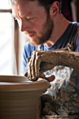 WHICHFORD POTTERY, WARWICKSHIRE: MAN MAKING HAND MADE TERRACOTTA CONTAINER IN WORKSHOP