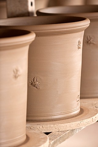 WHICHFORD_POTTERY_WARWICKSHIRE_DETAIL_OF_ARMSCOTE_BEE_ON_TERRACOTTA_CONTAINERS_IN_WORKSHOP