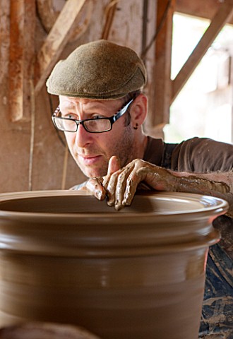 WHICHFORD_POTTERY_WARWICKSHIRE_ADAM_KEELING_THROWING_A_NEWLY_HANDMADE_TERRACOTTA_CONTAINER_IN_THE_WO