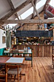 WHICHFORD POTTERY, WARWICKSHIRE: INSIDE THE CAFE WITH TABLES AND CHAIRS, KITCHEN BEHIND. WOOD FLOOR, BEAM, BEAMS