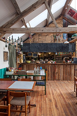 WHICHFORD_POTTERY_WARWICKSHIRE_INSIDE_THE_CAFE_WITH_TABLES_AND_CHAIRS_KITCHEN_BEHIND_WOOD_FLOOR_BEAM