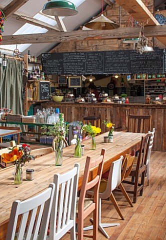 WHICHFORD_POTTERY_WARWICKSHIRE_INSIDE_THE_CAFE_WITH_TABLES_AND_CHAIRS_KITCHEN_BEHIND_WOOD_FLOOR_BEAM