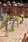 WHICHFORD POTTERY, WARWICKSHIRE: THE CAFE - WOODEN TABLE AND CHAIRS WITH GLASS VASES FILLED WITH FLOWERS