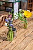 WHICHFORD POTTERY, WARWICKSHIRE: THE CAFE - WOODEN TABLE WITH GLASS VASES FILLED WITH FLOWERS - YELLOW TULIP, SNAKES HEAD FRITILLARY AND BLUEBELLS