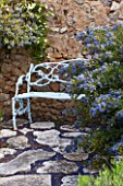 LA JEG, PROVENCE, FRANCE: DESIGNER ANTHONY PAUL - BLUE METAL BENCH, SEAT BY WALL WITH CEANOTHUS YANKEE POINT. MEDITERRANEAN, GARDEN, PROVENCE, MAY, PAVING, CRAZY