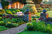 PETTIFERS, OXFORDSHIRE: PATH DOWN TO LAWN WITH PEDESTALS WITH LEAD URNS, TULIP BLACK PARROT, CORNUS ALTERNIFOLIA ARGENTEA. ENGLISH, COUNTRY, GARDEN, CLASSIC, SPRING, MAY