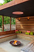 PRIVATE GARDEN LONDON DESIGNED BY LUCY WILLCOX AND ANA SANCHEZ MARTIN:FIRE PIT, PERGOLA WITH WOODEN BENCH SEATING, CUSHIONS, COVERED SEATING AREA, WALL, RELAXING