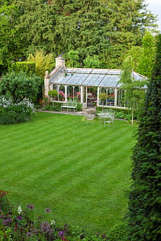 THE_LODGE_BURFORD_OXFORDSHIRE_THE_PELARGONIUM_FILLED_CONSERVATORY_WITH_BETULA_PENDULA_ON_LAWN_AND_EV
