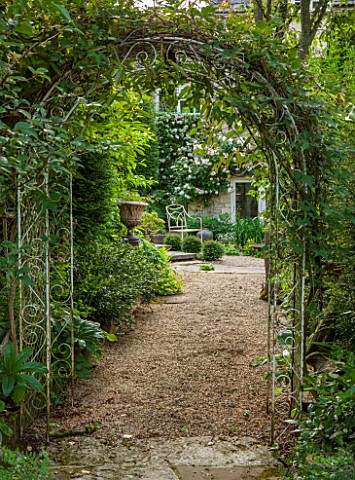 THE_LODGE_BURFORD_OXFORDSHIRE_VIEW_THROUGH_METALWORK_ARCHWAY_WITH_CLEMATIS_ROSA_PENELOPE_ON_HOUSE_WA