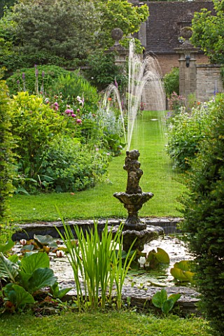 PYTTS_PLACE_BURFORD_OXFORDSHIRE_TIERED_STONE_FOUNTAIN_IN_POOL_WITH_WATERLILIES_AND_IRIS_SIBIRICA_BOR