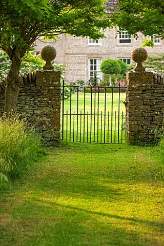 OXLEAZE_FARM_OXFORDSHIRE_GRASS_PATH_AND_VIEW_FROM_THE_ORCHARD_WITH_METAL_GATE_AND_ROBINIA_INERMIS_SU
