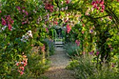 EASTLEACH HOUSE, GLOUCESTERSHIRE: WALLED GARDEN. GRAVEL PATH WITH ARCH, NEPETA SIX HILLS GIANT, ROSA PRINCESS LOUISE AND ROSA DOROTHY PERKINS. RAMBLING, RAMBLER, ARCHWAY