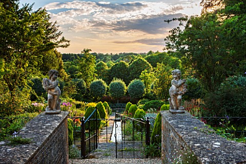 EASTLEACH_HOUSE_GLOUCESTERSHIRE_VIEW_THROUGH_GATES_DOWN_THE_RILL_TO_SORBUS_ARIA_LUTESCENS_STATUES_ST