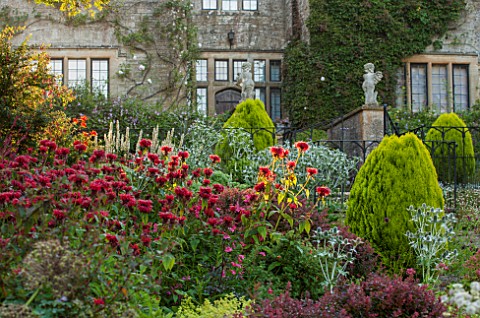 EASTLEACH_HOUSE_GLOUCESTERSHIRE_WEST_FACADE_OF_HOUSE_WITH_RED_BORDER__MONARDA_SQUAW_ERYNGIUMS_PLATYC