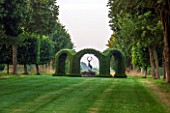 EASTLEACH HOUSE, GLOUCESTERSHIRE: LAWN AND AVENUE OF TILIA PLATYPHYLLOS RUBRA WITH CENTRAL YEW RONDEL ENCLOSING BRONZE STAG SCULPTURE. ENGLISH, GARDEN