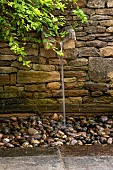 CALENDARS: BURFORD,OXFORDSHIRE: WATER CASCADES INTO PEBBLE POOL FROM MOUTH OF RILL SET INTO DRY STONE WALL. WATER FEATURE.