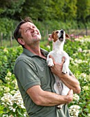 THE REAL FLOWER COMPANY: ROB HOLDING HIS DOG BIFFY IN THE ROSE PADDOCK. MAN, CUT, FLOWERS, CUTTING, GARDEN, SUMMER, HYDRANGEAS
