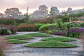 HAUSER & WIRTH, SOMERSET: THE OUDOLF FIELD, DURSLADE FARM - PATHS BESIDE TURF MOUNDS AND NEW PERENNIAL BORDERS BY PIET OUDOLF - SUNRISE, DAWN, GRASS, PATH
