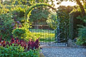 MORTON HALL GARDENS, WORCESTERSHIRE: KITCHEN GARDEN IN LATE SUMMER. BEDS WITH AMARANTHUS, METAL GATE, WALL, WALLED, COUNTRY, HOUSE, CLASSIC, VEGETABLE, ARCH, DARK, AMARANTHUS