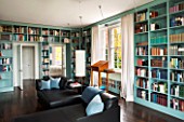 MORTON HALL, WORCESTERSHIRE: LIBRARY WITH VIEWS OF SOUTH GARDEN.SHELVES BY WIENER WERKSTAETTEN,PAINTED IN FB DIX BLUE.CHERRY WOOD LECTERN.BLACK LEATHER RECAMIERE SOFAS