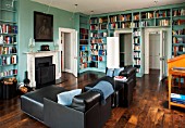 MORTON HALL, WORCESTERSHIRE: LIBRARY WITH VIEWS OF SOUTH GARDEN.SHELVES BY WIENER WERKSTAETTEN,PAINTED IN FB DIX BLUE.CHERRY WOOD LECTERN.BLACK LEATHER RECAMIERE SOFAS,FIREPLACE