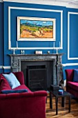 MORTON HALL,WORCESTERSHIRE:LIVING ROOM IN AZURE BLUE.18TH CENTURY FIRE SURROUND IN ITALIAN MARBLE. MAGENTA VELVET SOFAS BY DONGHIA.PAINTING VINEYARD NEAR ST JEAN PLA DE CORT