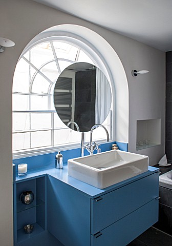 MORTON_HALL_WORCESTERSHIRE_BATHROOM_WITH_ARCHED_WINDOW_FREE_STANDING_CIRCULAR_MIRROR_AND_BLUE_PAINTE