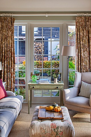 THE_COACH_HOUSESURREY_GARDEN_ROOM_WITH_VIEW_OF_PATIOLOGSTORE_SOFAS_CHAIR_SIDE_TABLE_FABRIC_FOOTSTOOL