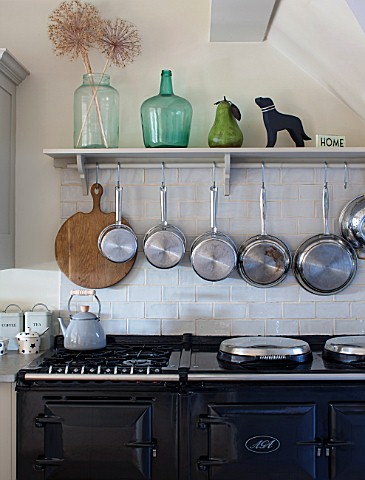 THE_COACH_HOUSESURREY_THE_KITCHEN_WITH_DETAIL_OF_SHELF_WITH_HANGING_POTS_AND_PANS_ABOVE_BLACK_AGA_DE