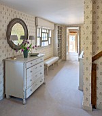 THE COACH HOUSE,SURREY: BEDROOM. SHABBY CHIC CHEST OF DRAWERS FROM THREE GATES GALLERY, MIRROR FROM INDIA JANE, BENCH FROM CHELSEA TEXTILES. NEUTRAL DECOR, WALLPAPER, CARPET.