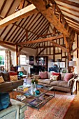 THE COACH HOUSE,SURREY: FAMILY ROOM WITH EXPOSED OAK BEAMS AND PIANO. SOFAS, LARGE GLASS COFFEE TABLE, BEAUTIFUL RUG ON WOODEN FLOOR. RELAX, READING ROOM, MUSIC ROOM.