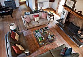 THE COACH HOUSE,SURREY: OVERVIEW OF FAMILY ROOM WITH SOFAS, LARGE GLASS COFFEE TABLE, BEAUTIFUL RUG ON WOODEN FLOOR AND FIREPLACE. RELAX, COSY, READING ROOM