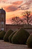 BURTON AGNES HALL, EAST YORKSHIRE: CHRISTMAS - THE GATEHOUSE AT SUNRISE - MORNING LIGHT, YEW, TAXUS BACCATA, CLIPPED, TOPIARY, DRIVEWAY, FAIRY LIGHTS, CLASSIC, FORMAL