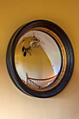 THE FREETH, HEREFORDSHIRE: HALLWAY - PRINT ROOM YELLOW FROM FARROW AND BALL PAINTED WALL, BLACK AND GOLD RIMMED CONVEX MIRROR