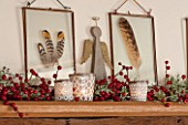 THE FREETH, HEREFORDSHIRE: KITCHEN, DINER - ANGELS, BERRIES AND GLASS FRAMED FEATHER HANGINGS ON MANTELPIECE. CHRISTMAS, DECORATIONS, CANDLES