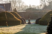 ABLINGTON MANOR, GLOUCESTERSHIRE: FEBRUARY VIEW AT SUNRISE - SUNDIAL, LAWN AND TOPIARY. FORMAL, ENGLISH, GARDEN, EARLY SPRING