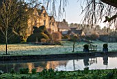 ABLINGTON MANOR, GLOUCESTERSHIRE:IEW ACROSS RIVER COLN TO MANOR HOUSE. FEBRUARY, EARLY SPRING, LATE WINTER, WATER, RIVER, COUNTRY, GARDEN, ENGLISH, TOPIARY